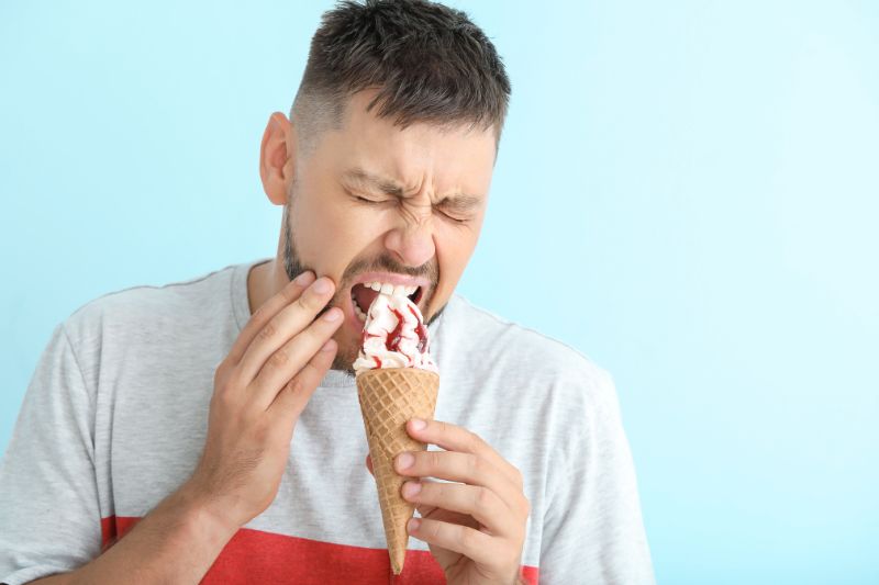 Hombre con sensibilidad dental al comer un helado frío en Carrero & Tezza León